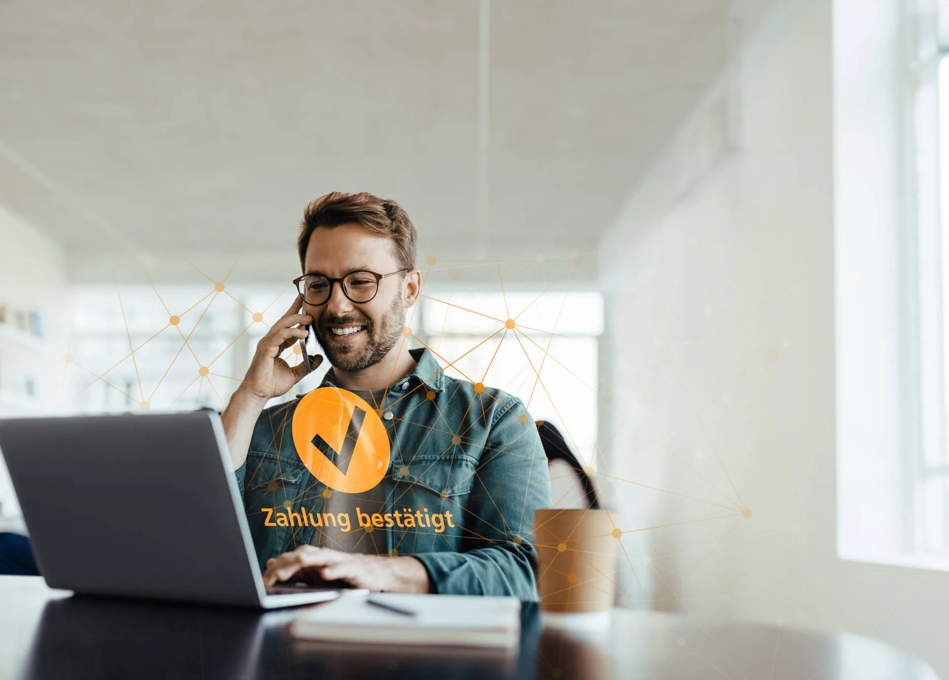 Mann am telefonieren, sitzend am Laptop mit der Benachrichtigung "Zahlung bestätigt"